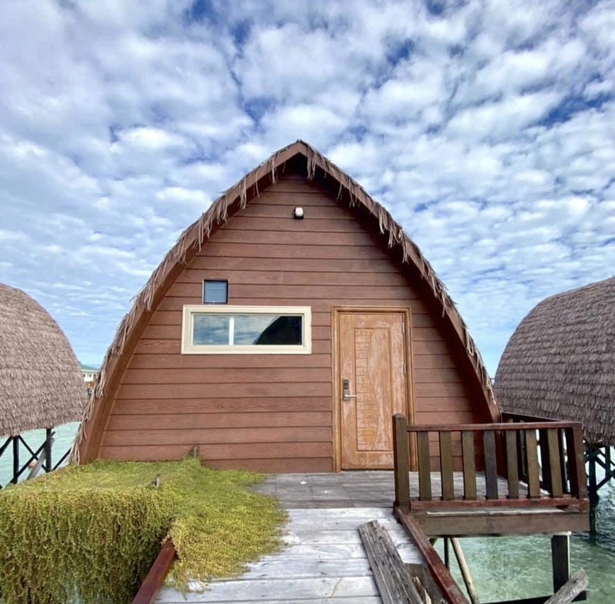 A timber-clad chalet with a traditional Sabah style pointed roof with thatched trim and wooden entrance door at Crystal Resort
