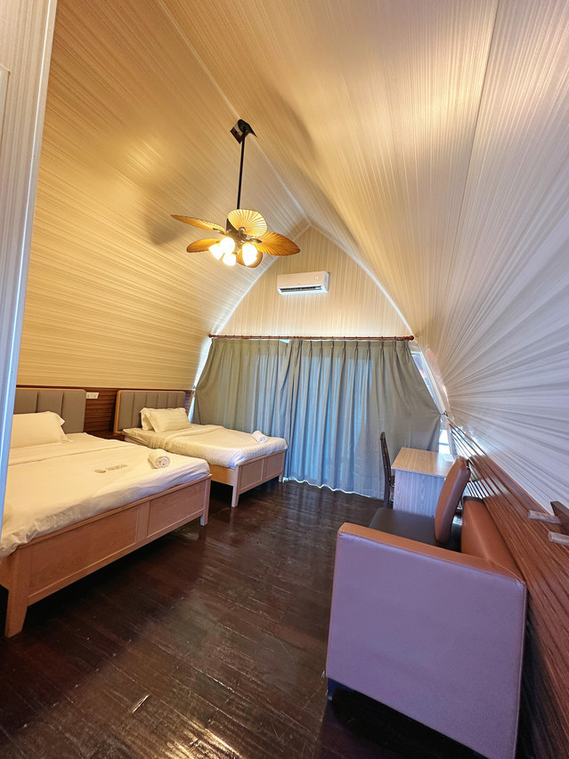 A spacious family room at Crystal Resort in the Semporna islands with two large beds, modern decor, elegant hardwood floors and sliding glass doors to the balcony