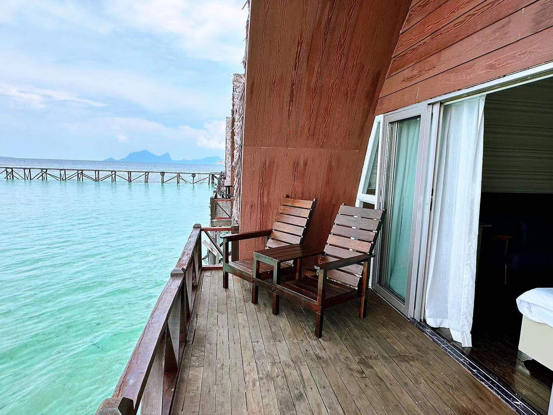 Private oceanview balcony at Crystal Resort featuring wooden seating and uninterrupted views of the Tun Sakaran Marine Park