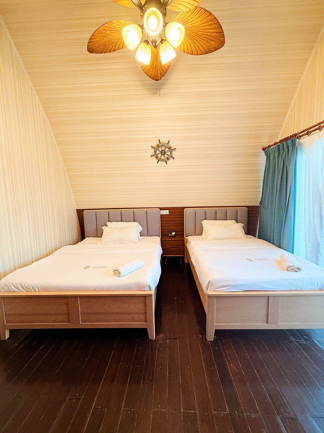 A beautiful bedroom at Crystal Resort with two large beds, modern design, smooth timber floors and panoramic glass doors framing the seaviews